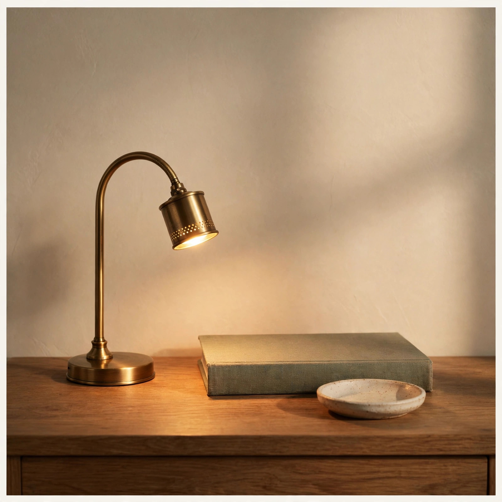 A small arched brass reading lamp glowing on a nightstand beside a book